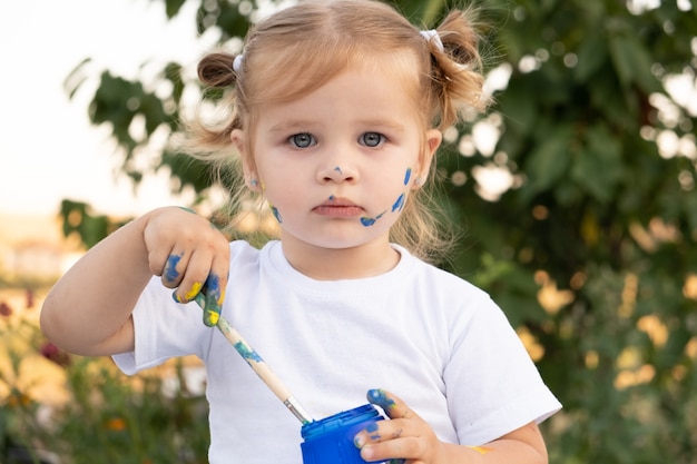 menina loira com um pote de tinta e um pincel