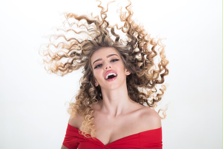 Foto menina loira de cabelo comprido com cabelo encaracolado. retrato de menina positiva com cabelo encaracolado, isolado no fundo branco. maquiagem e cosméticos para cuidar da pele. beleza e estilo. cuidado profissional do cabelo.