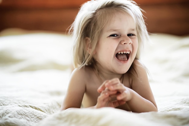 Menina loira deitada na cama criança emocional posando