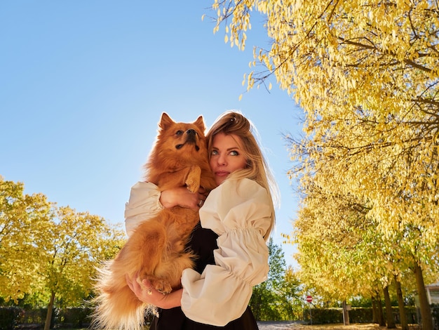 Menina loira e bonita brincando com cachorro da Pomerânia