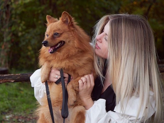 Menina loira e bonita brincando com cachorro da pomerânia