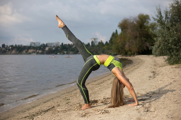 Menina loira fazendo yoga na margem do rio