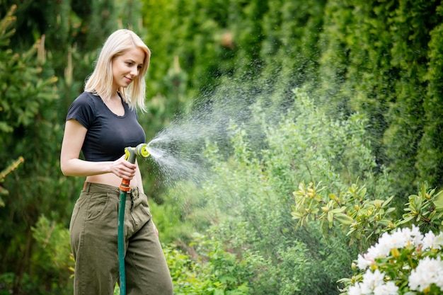 Foto menina loira regando seu jardim no verão