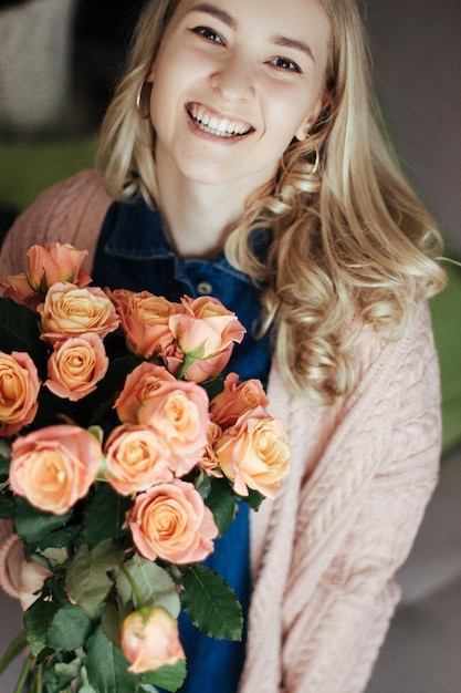 Menina loira sorri abertamente com flores na mão. Vista do topo