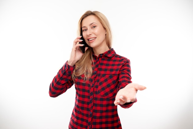 Menina loira sorridente alegre em smartphone falante casual em fundo branco do estúdio