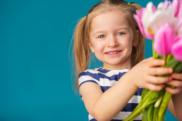 Menina loira sorridente com buquê de tulipas