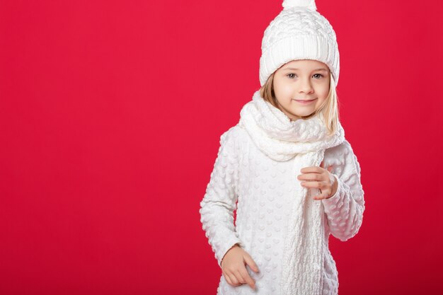 Menina loira sorridente em um chapéu branco e lenço no vermelho