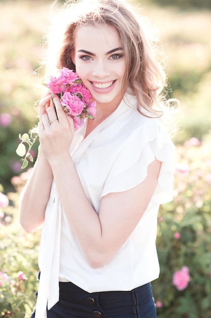 Menina loira sorridente segurando rosas no campo