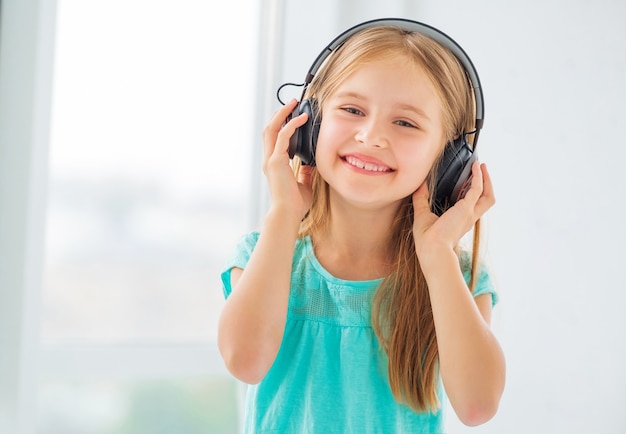 Menina loira sorrindo e ouvindo música em fones de ouvido