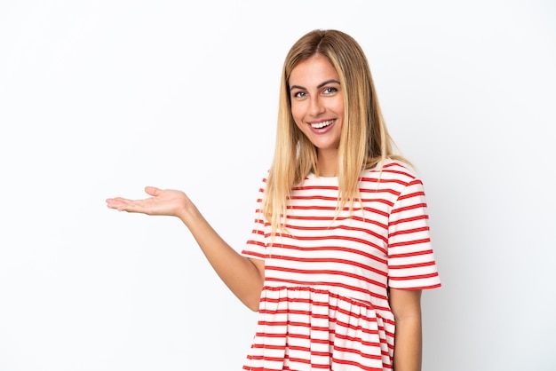 Menina loira uruguaia isolada em fundo branco apresentando uma ideia enquanto olha sorrindo para