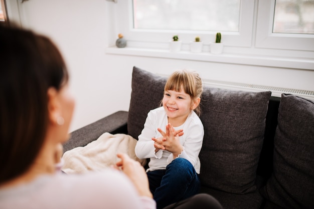 Menina loura adorável que tem o divertimento em casa. Tempo para a família.