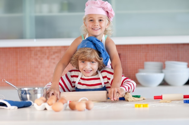 Menina loura cozinhando com seu irmãozinho