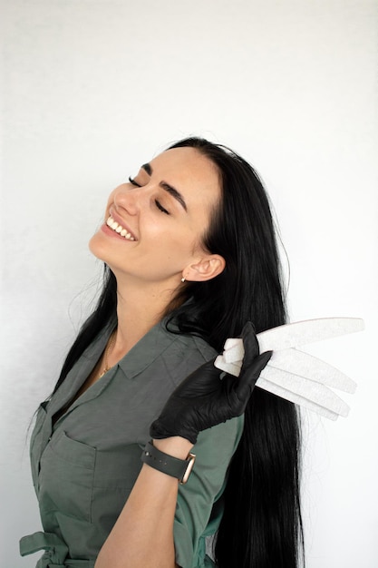 Menina manicure sorrindo e segurando arquivos de unhas espaço de fundo de parede branca para texto Conceito de salão de beleza de área de serviço