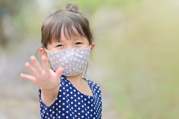 Menina mão parar sinal quando criança sair de casa criança com uma máscara no nariz para atividades ao ar livre de segurança