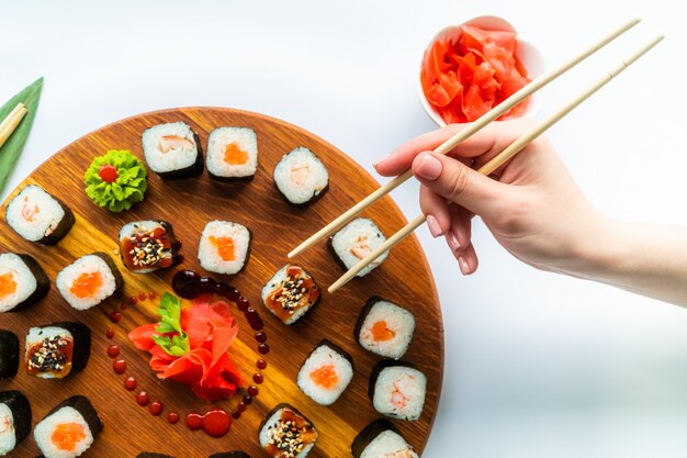 Foto menina mão segura sushi acima da superfície de madeira