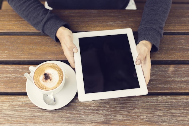 Menina, mãos, com, tablete digital, e, xícara café, ligado, um, tabela madeira