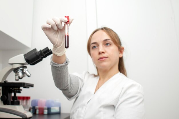 Menina médica no laboratório segura tubo de ensaio com exames de sangue e olha para ele mulher enfermeira no trabalho