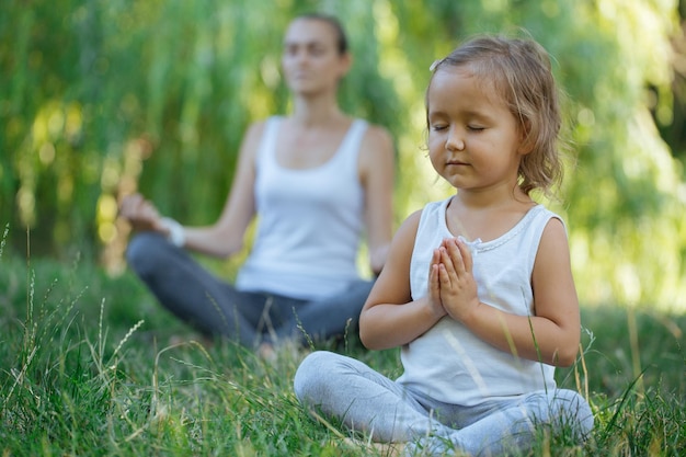 Menina meditando com a mãe no campo