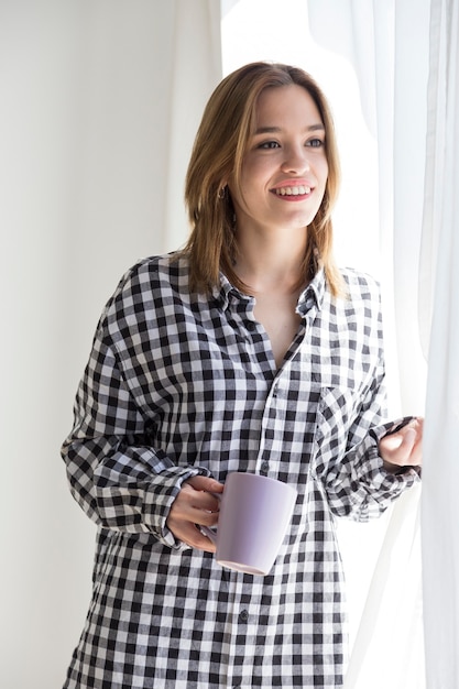 Menina melancólica tomando café olhando pela janela