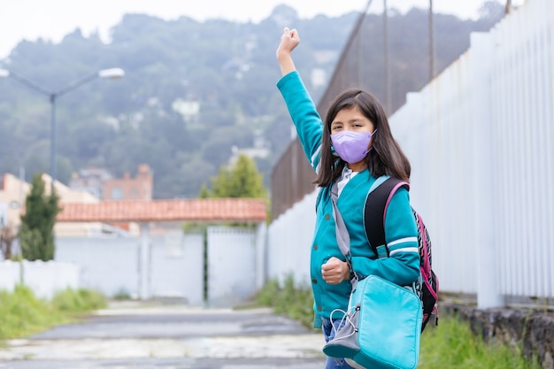 Menina mexicana animada de volta às aulas usando máscara protetora após bloqueio por coronavírus