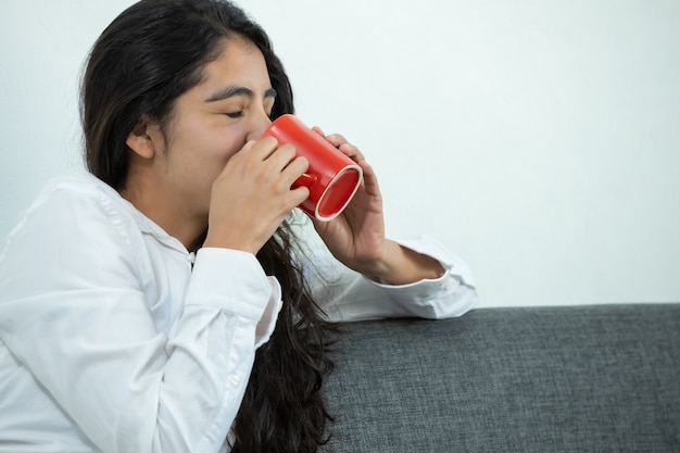 Menina mexicana tomando café na caneca vermelha