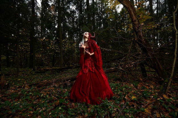 Menina modelo elegante e moderna na imagem de Malévola posando entre a floresta mística - história de conto de fadas, cosplay. Dia das Bruxas.