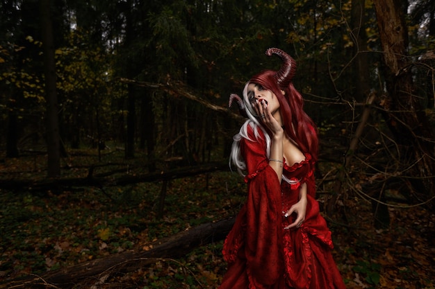 Menina modelo elegante e moderna na imagem de Malévola posando entre a floresta mística - história de conto de fadas, cosplay. Dia das Bruxas.