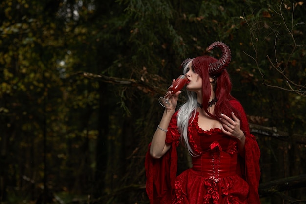 Menina modelo elegante e moderna na imagem de Malévola posando entre a floresta mística - história de conto de fadas, cosplay. Dia das Bruxas.