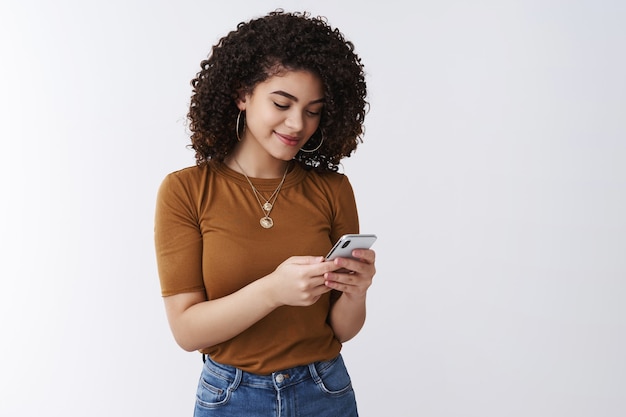 Foto menina moderna e elegante verificando a caixa de correio segurando a tela do telefone do smartphone sorrindo encantada mensagem escrevendo postar página de mídia social aplicativo de alimentação de rolagem fundo branco