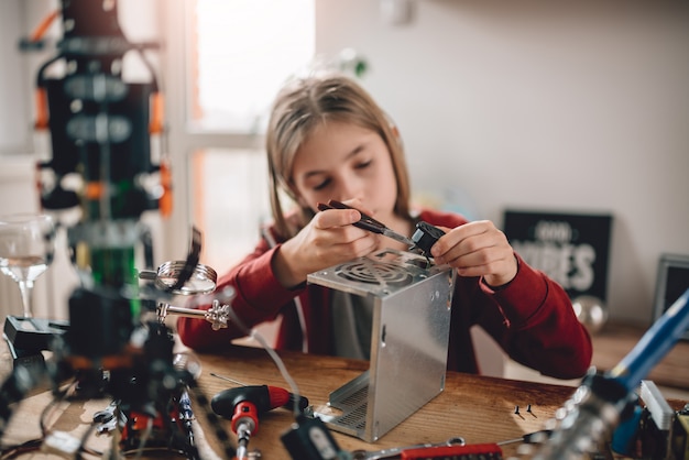 Menina modificando a fonte de alimentação e aprendendo robótica