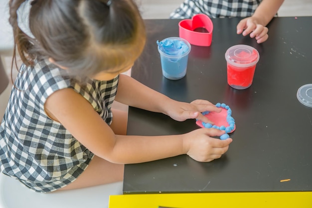 Menina moldando argila colorida para alguns produtospensar da imaginação conceito de brincadeira de crianças felizes