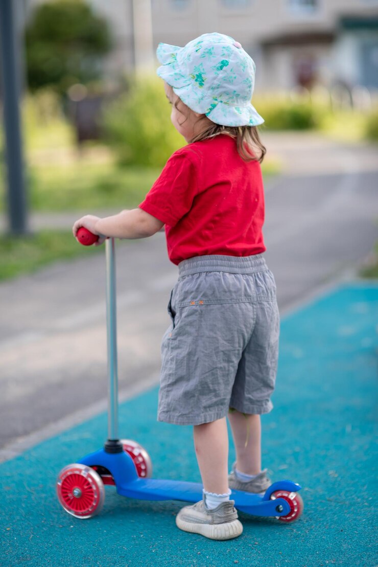 Foto menina montando uma scooter sozinha em um playground no verão