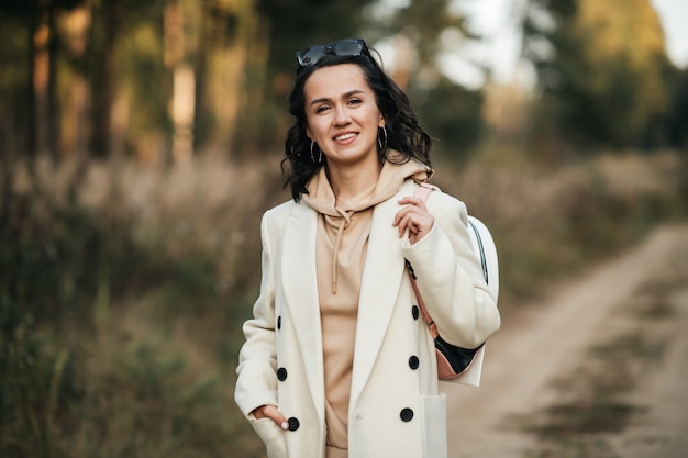 menina morena com mochila no caminho da floresta