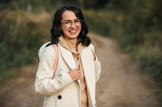 menina morena com mochila no caminho da floresta