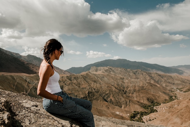 Foto menina morena com óculos de sol, olhando para um vale