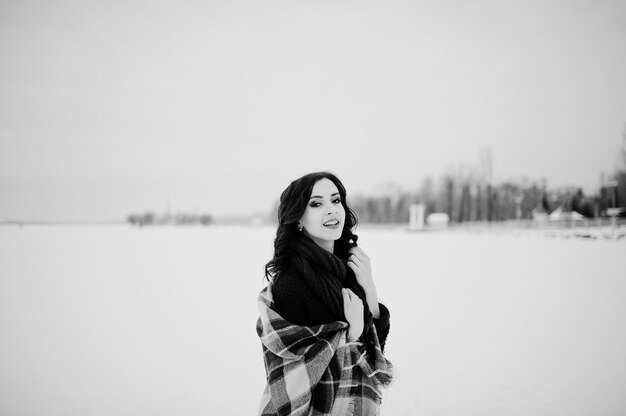 Menina morena de suéter verde e lenço vermelho com lago congelado ao ar livre xadrez na noite dia de inverno.