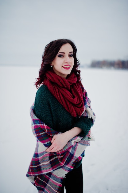 Menina morena de suéter verde e lenço vermelho com lago congelado ao ar livre xadrez na noite dia de inverno.