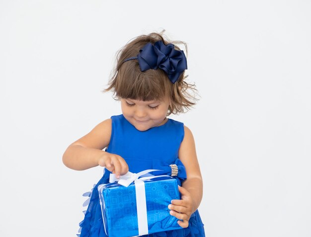 Menina morena de vestido azul desata a caixa de presente