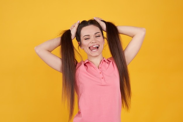 Menina morena divertidamente segurando o cabelo amarelo.