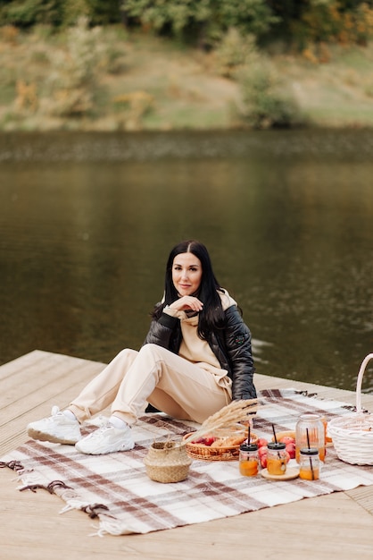 Menina morena elegante com uma jaqueta de couro, calça bege e tênis branco no lago