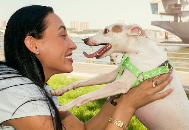 Menina morena feliz, segurando um cachorro