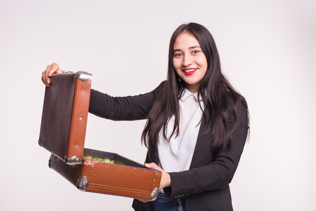 Menina morena feliz vestindo roupas formais, abrindo uma mala retrô em estúdio leve