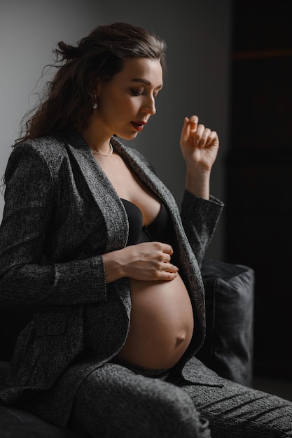 Menina morena grávida elegante com calça cinza forte jaqueta