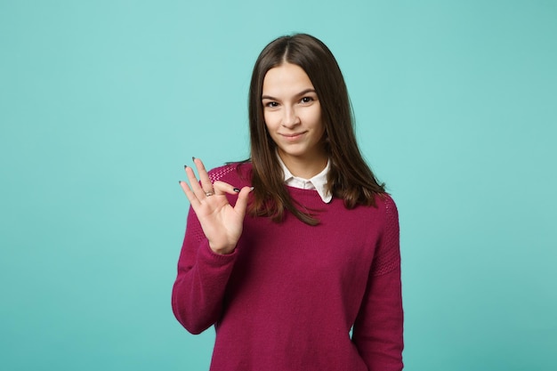 Menina morena jovem em roupas casuais posando isolado no retrato de estúdio de fundo de parede azul verde turquesa. Conceito de estilo de vida de emoções sinceras de pessoas. Mock up espaço de cópia. Mostrando o gesto certo