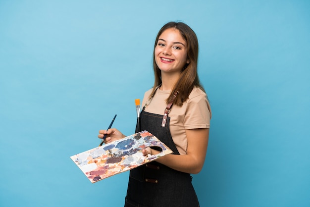 Menina morena jovem isolado parede azul segurando uma paleta