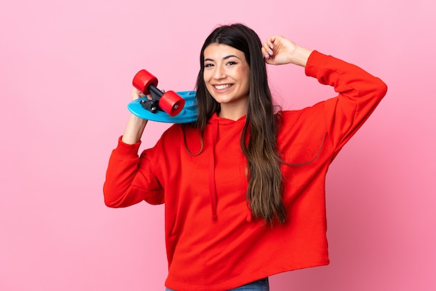 Menina morena jovem isolado rosa com um skate