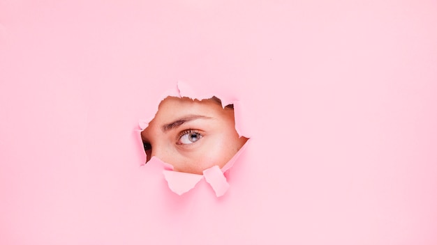 Foto menina morena posando através de um buraco de papel