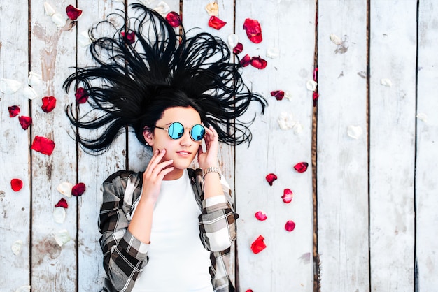 Menina morena relaxante no chão de madeira ao ar livre