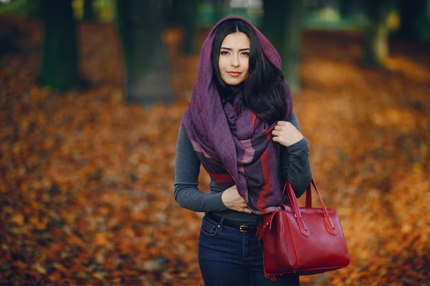 menina morena relaxante no parque durante o outono