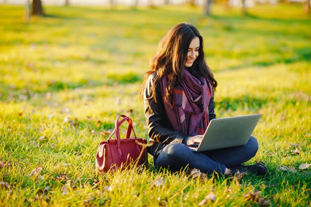 menina morena trabalhando em seu laptop no parque durante o outono